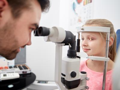 Billede af en læge som kigger i et barn i øjet