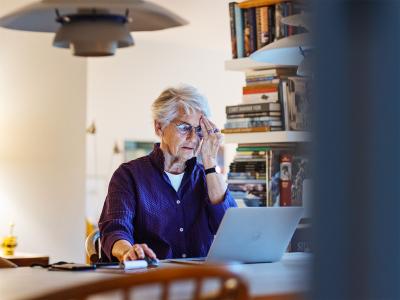 Ældre kvinde som sidder med sin bærbar computer