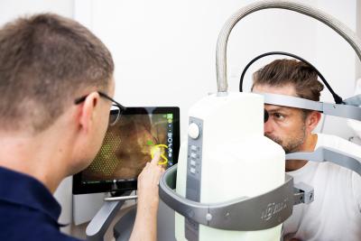 Billede af en øjenlæge der igang med at undersøge en patients øjne