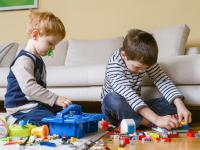 To børn der sidder på gulvet og leger med lego.