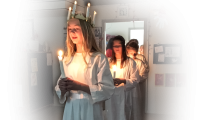 Billede af 3 piger der går på lang linje, de er klædt i hvide kjoler, den første pige har en grankrans på hovedet med 4 tændte stearinlys i.