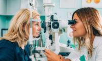 En kvinde der bliver undersøgt i øjet af en optiker